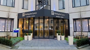 The exterior of a Holiday Inn Express hotel with a modern facade, large glass entrance, and potted plants at the entrance. - Holiday Inn Express Amsterdam - Schiphol by IHG (Hoofddorp)