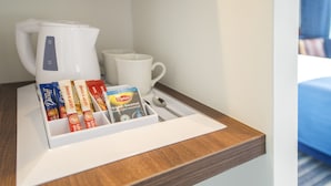 A hotel room's breakfast area with a coffee maker, a white mug, and a tray with breakfast items including Lipton tea and English Breakfast tea. - Holiday Inn Express Amsterdam - Schiphol by IHG (Hoofddorp)