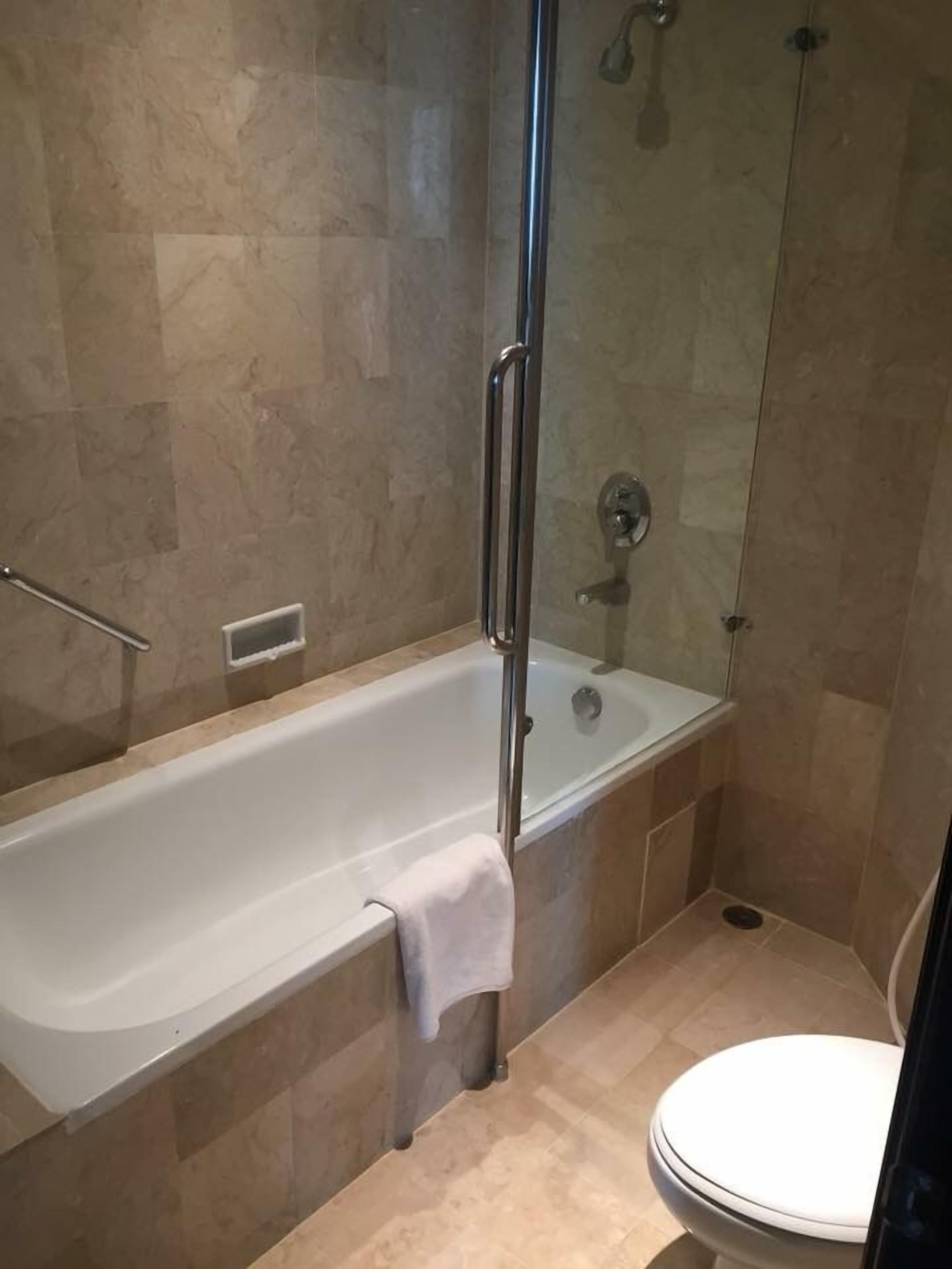 A bathroom with a bathtub, a glass-enclosed shower, and a toilet.