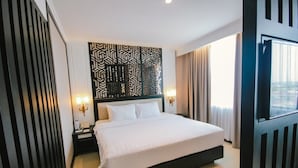 Camera d'hotel moderna con un letto grande, un pannello decorativo, due lampade da comodino e una finestra con tende.