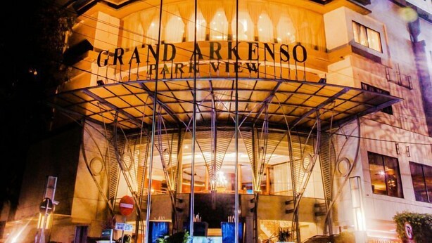 Un hotel con una facciata curva e insegne illuminate che riportano la scritta "Grand Arkenso".