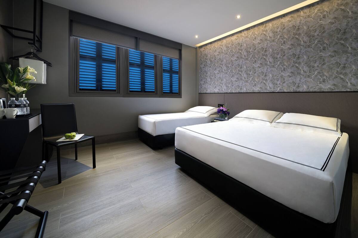 Een moderne hotelkamer met twee bedden, een bureau en een stoel.