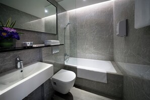 Een moderne badkamer met een wit wastafel, toilet en bad.