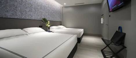 A modern hotel room with two beds, a flat-screen TV mounted on the wall, and a small seating area with a bench.