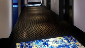 Un pasillo moderno con piso estampado, barandilla de metal y techo iluminado en azul.