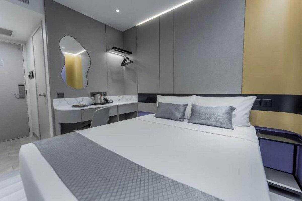 A modern hotel room with a large bed, a desk, and a mirror.