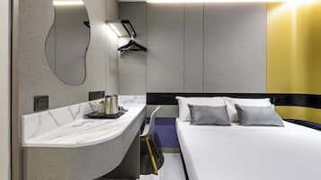 Una habitación de hotel moderna con una encimera curva de mármol, una cama con dos almohadas y un teléfono instalado en la pared.