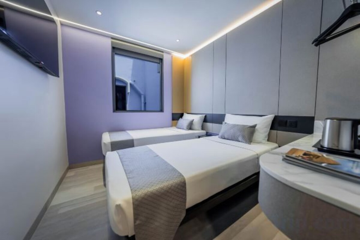 Une chambre d’hôtel moderne avec un lit, une table de chevet et une fenêtre.