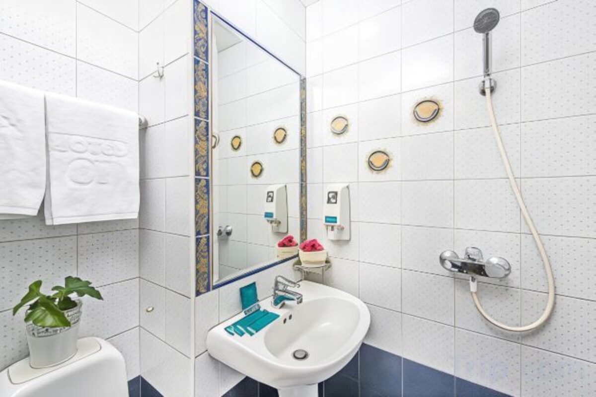Une salle de bain équipée d’un lavabo, d’un miroir, d’un porte-serviettes et d’une douche.
