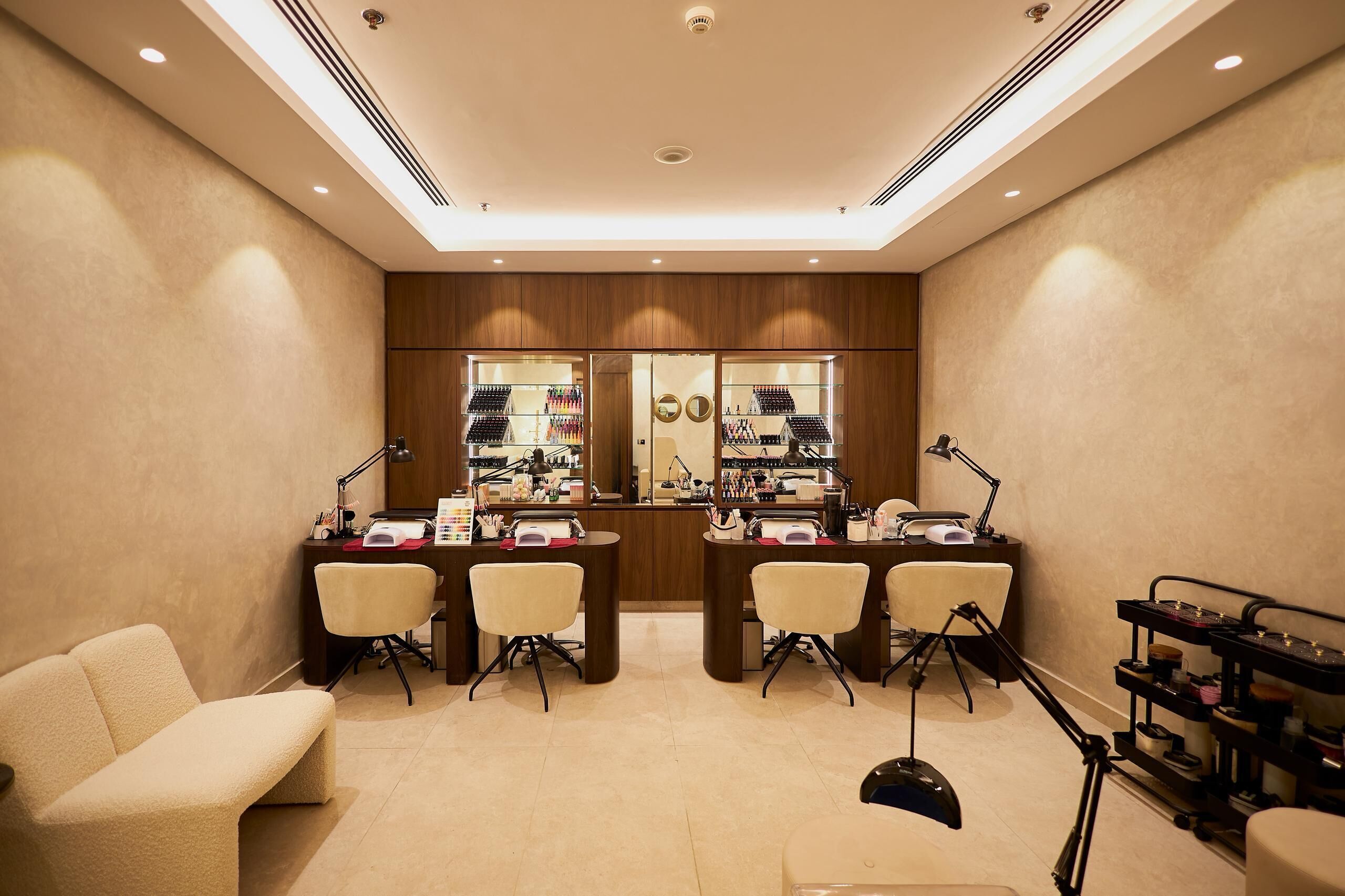 A well-lit, modern salon with two reception desks, a waiting area with a sofa, and a display of hair products.