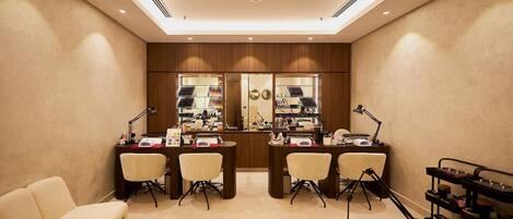 A well-lit, modern salon with two reception desks, a waiting area with a sofa, and a display of hair products.
