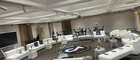 A modern hotel lobby with white sofas, a large screen, and a circular seating area with a TikTok logo.