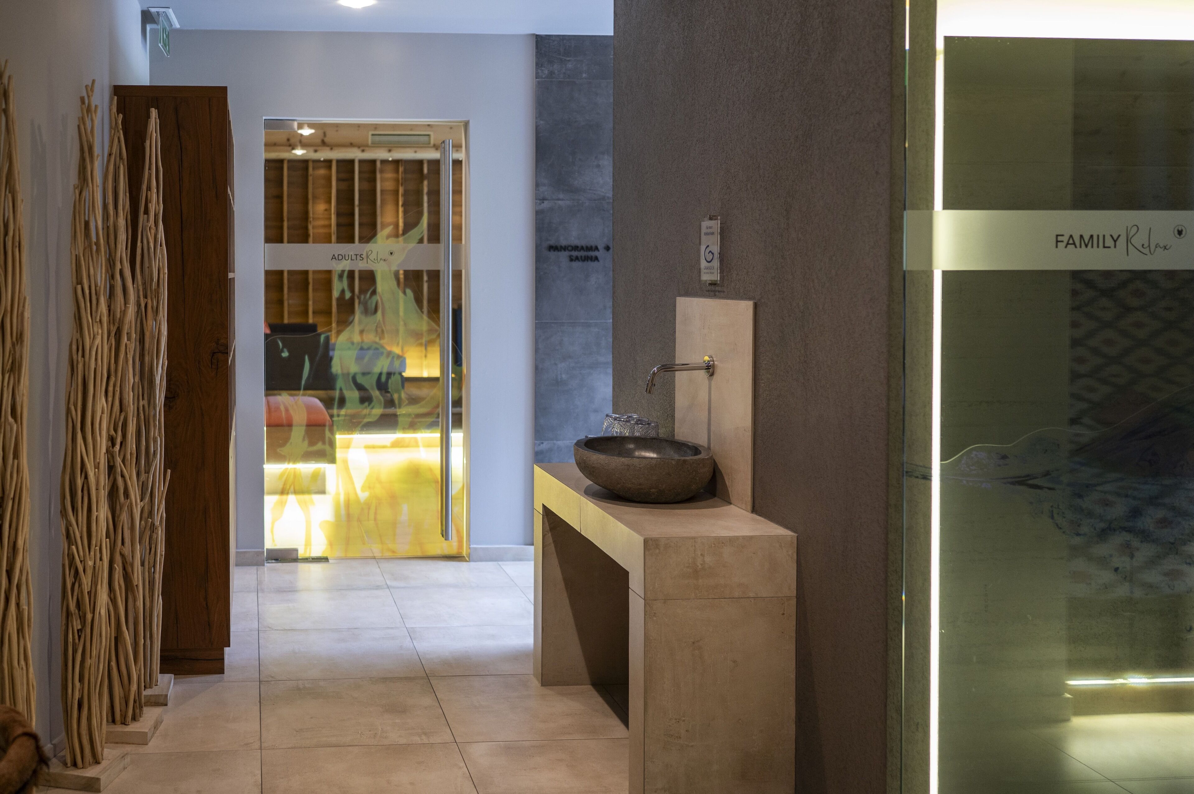 Un baño moderno con un lavabo de piedra, cabina de ducha con mampara de vidrio y puerta de madera.