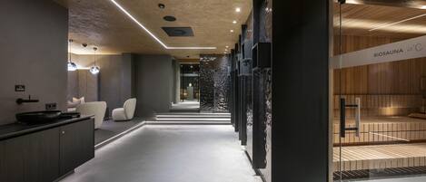 A modern spa area with a wooden sauna, a glass wall, and a minimalist design.