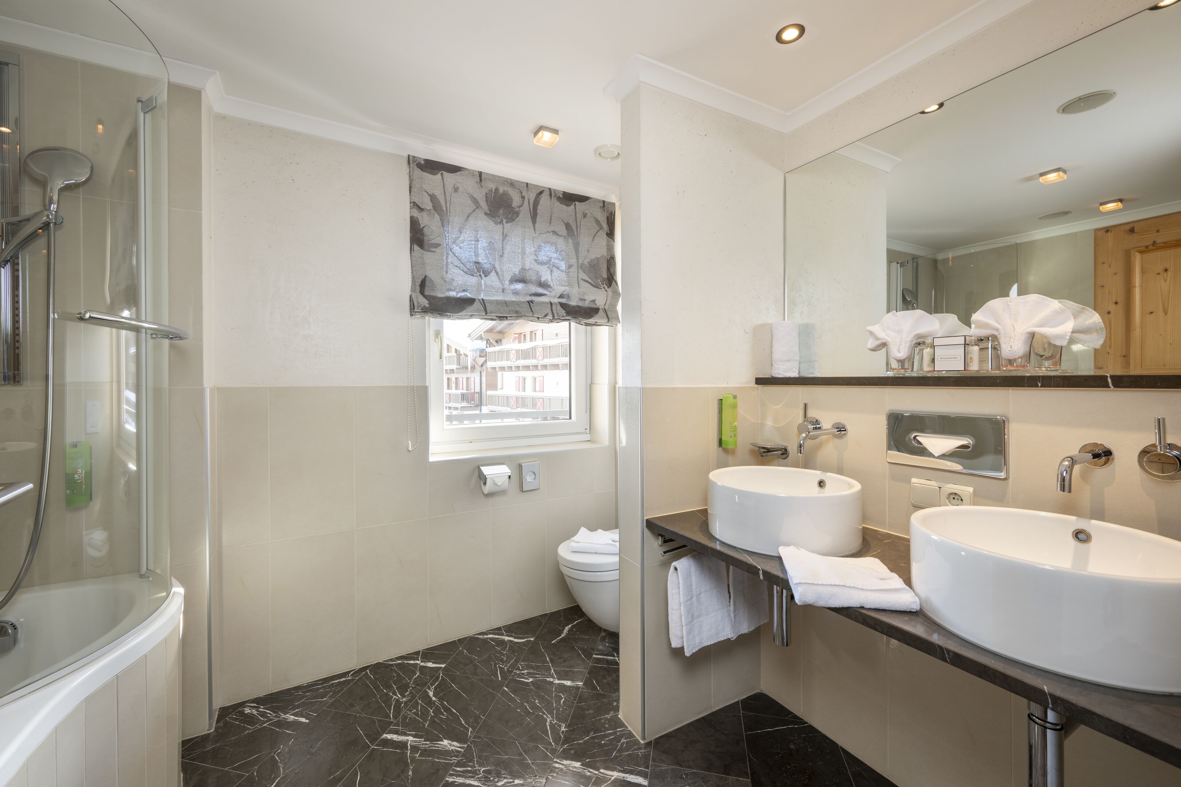 A modern bathroom with a glass-enclosed shower, two sinks, and a large mirror.