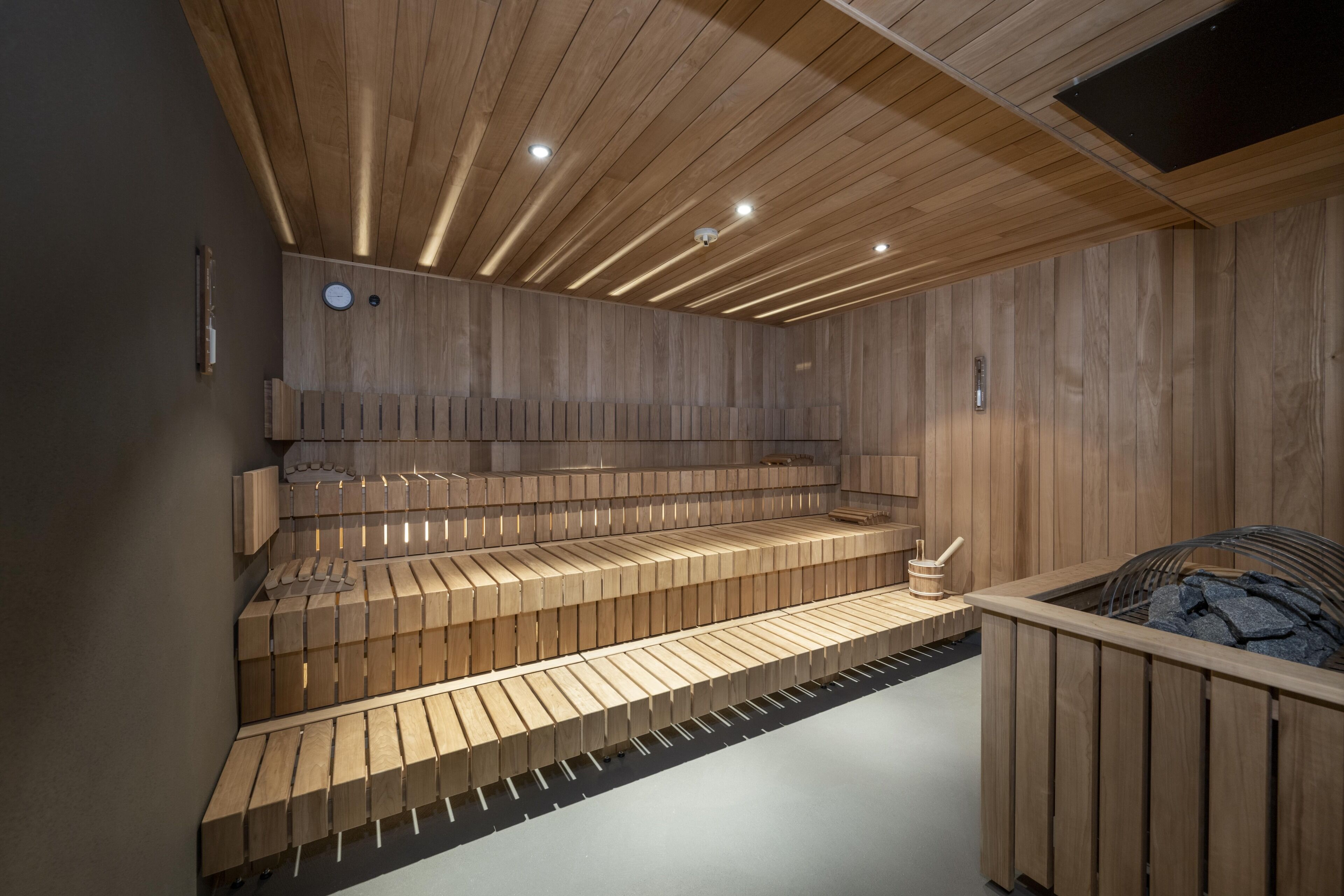 A sauna with wooden benches and a sloped floor.