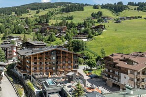 A mountain resort with multiple lodging buildings, outdoor seating, and a pool area. - Hotel Kendler (Saalbach-Hinterglemm)