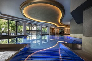 Una piscina cubierta, una piscina al aire libre, tumbonas