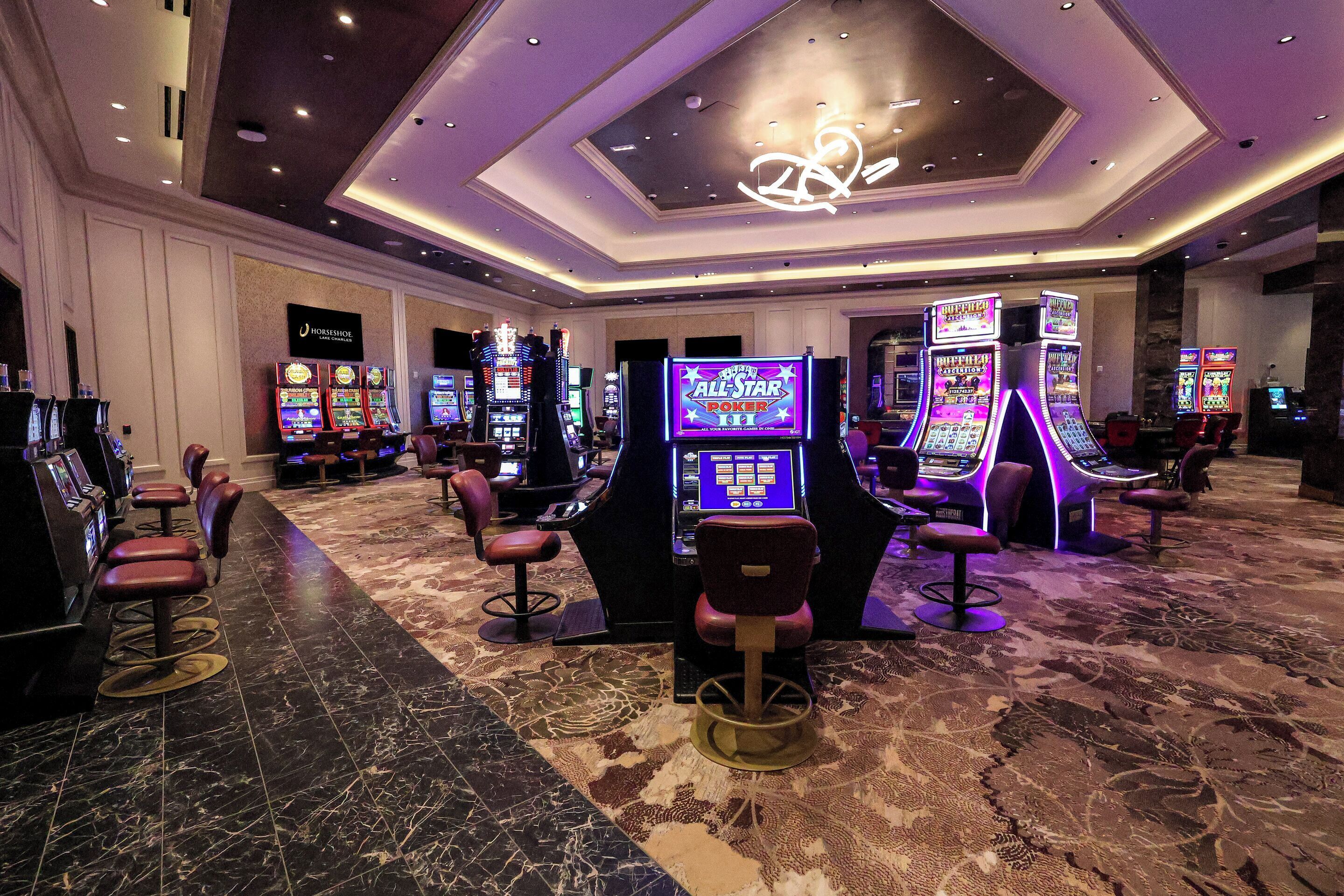 A casino area with slot machines, bar stools, and a neon sign for All Star Poker.