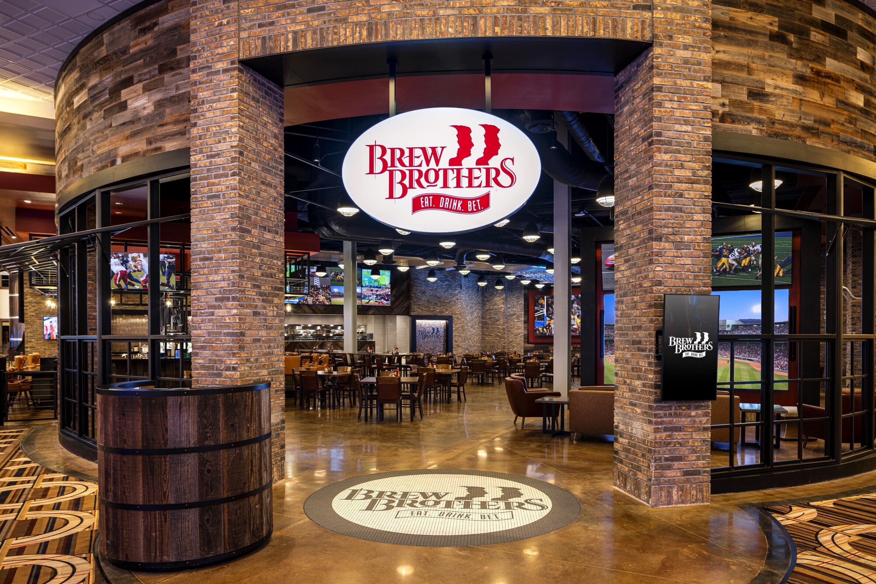 A Brew Brothers restaurant with a brick exterior, indoor seating, and a large logo on the floor.