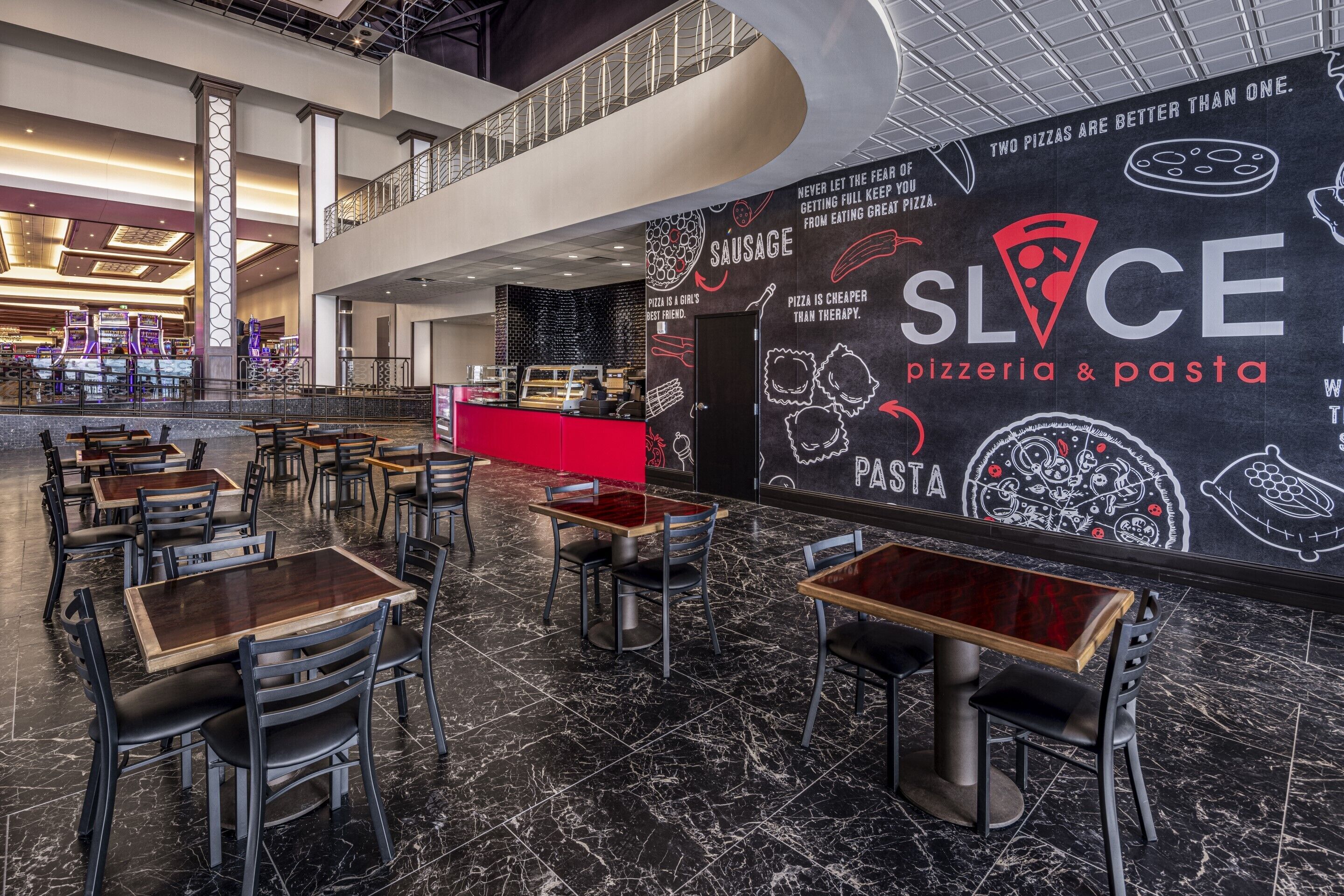A modern pizzeria interior with marble flooring, multiple dining tables, and a prominent pizza-themed wall.