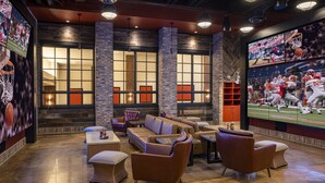 A spacious lounge area with leather sofas, a coffee table, and a flat-screen TV displaying sports. - Horseshoe Lake Charles Hotel & Casino -  A Caesars Rewards Destination (Westlake)