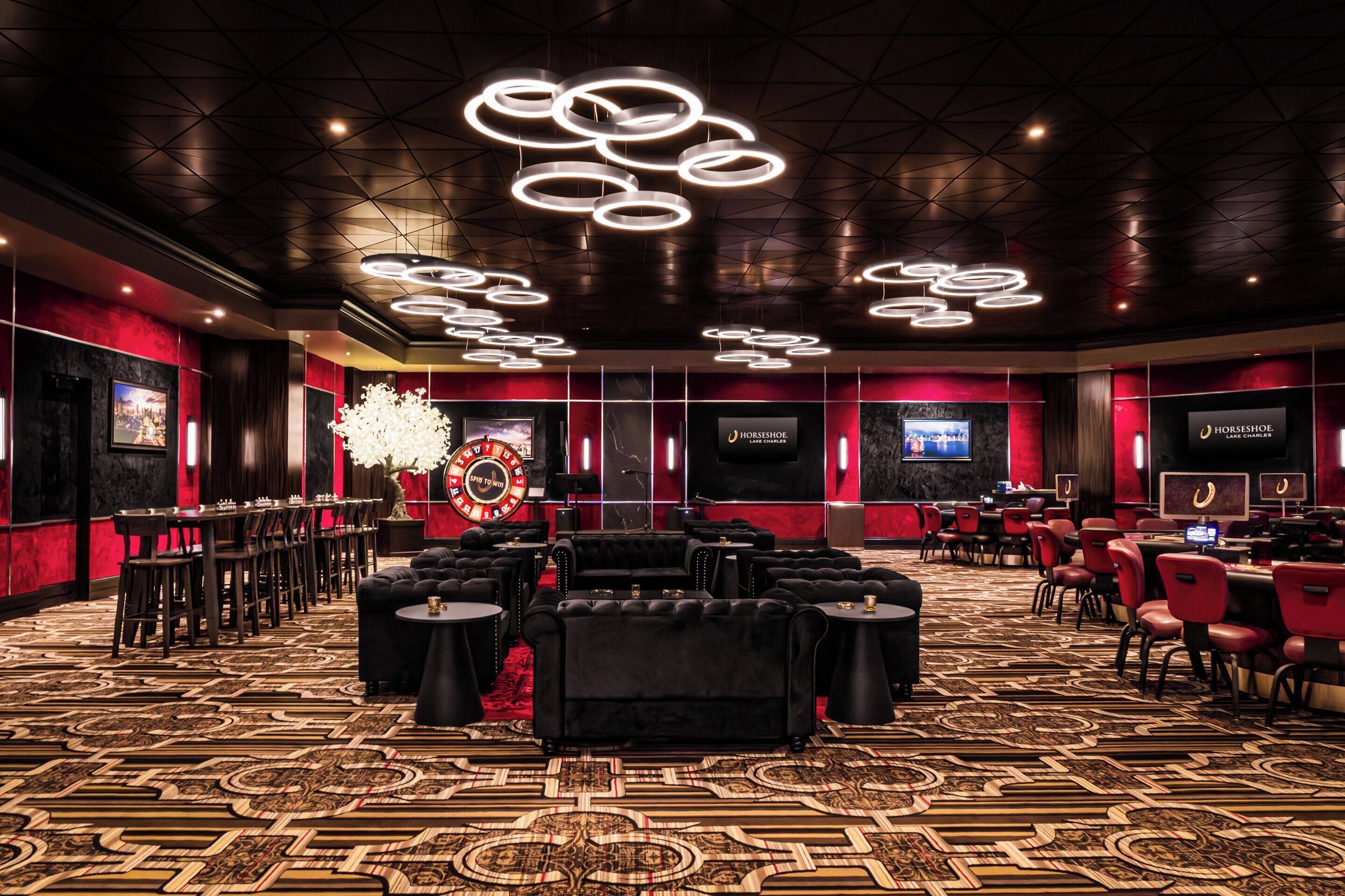 A spacious room with a patterned carpet, multiple seating areas, and a large chandelier.