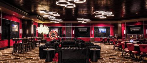 A spacious room with a patterned carpet, multiple seating areas, and a large chandelier.