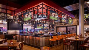 A bar area with multiple screens displaying sports content, a bar counter, and seating arrangements. - Horseshoe Lake Charles Hotel & Casino -  A Caesars Rewards Destination (Westlake)
