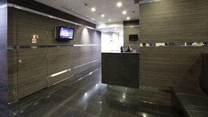 A modern hotel reception area with a flat-screen TV, a reception desk, and a no smoking sign. - Value Hotel Nice (Singapore)
