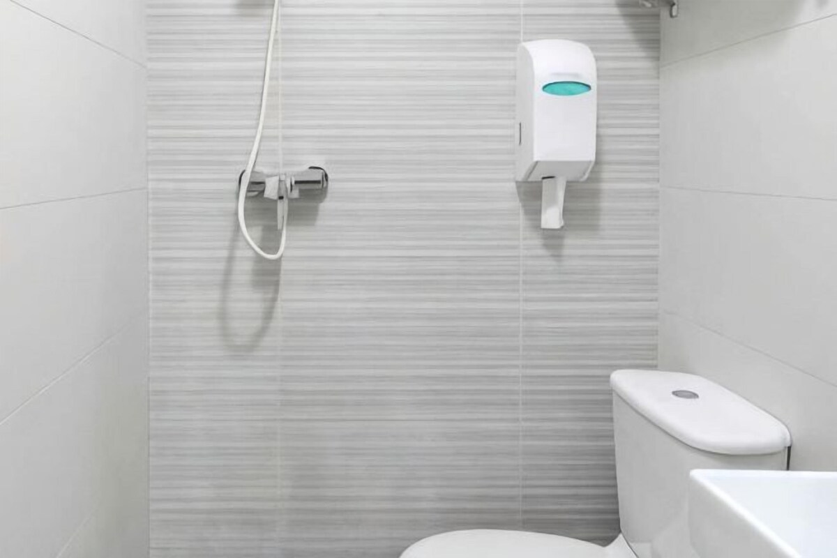 A bathroom with a toilet, a shower, and a hand dryer.