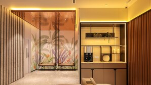 Un interior moderno con una zona de estar, una cafetera y una estantería con objetos decorativos.