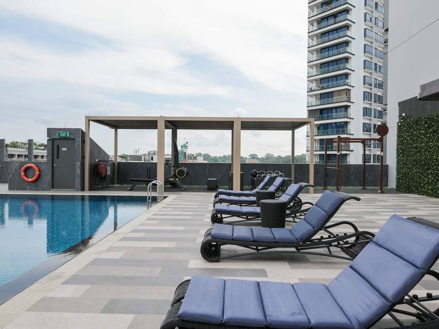 A rooftop pool area with lounge chairs, a covered seating area, and a high-rise building in the background.