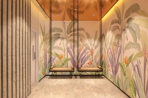 A hallway with a patterned wall, a marble floor, and a ceiling with recessed lighting.
