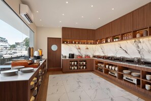 Una cocina moderna con encimeras de mármol, armarios de madera y diversos electrodomésticos.