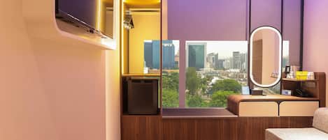 Une chambre d’hôtel moderne avec vue sur la ville, une télévision intégrée, une table de chevet et un miroir.