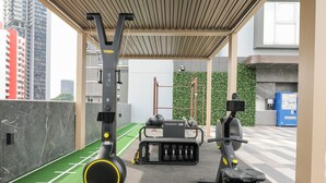 A gym with exercise equipment, a green artificial turf area, and a cityscape view. - Days Inn by Wyndham Singapore Novena (Singapore)