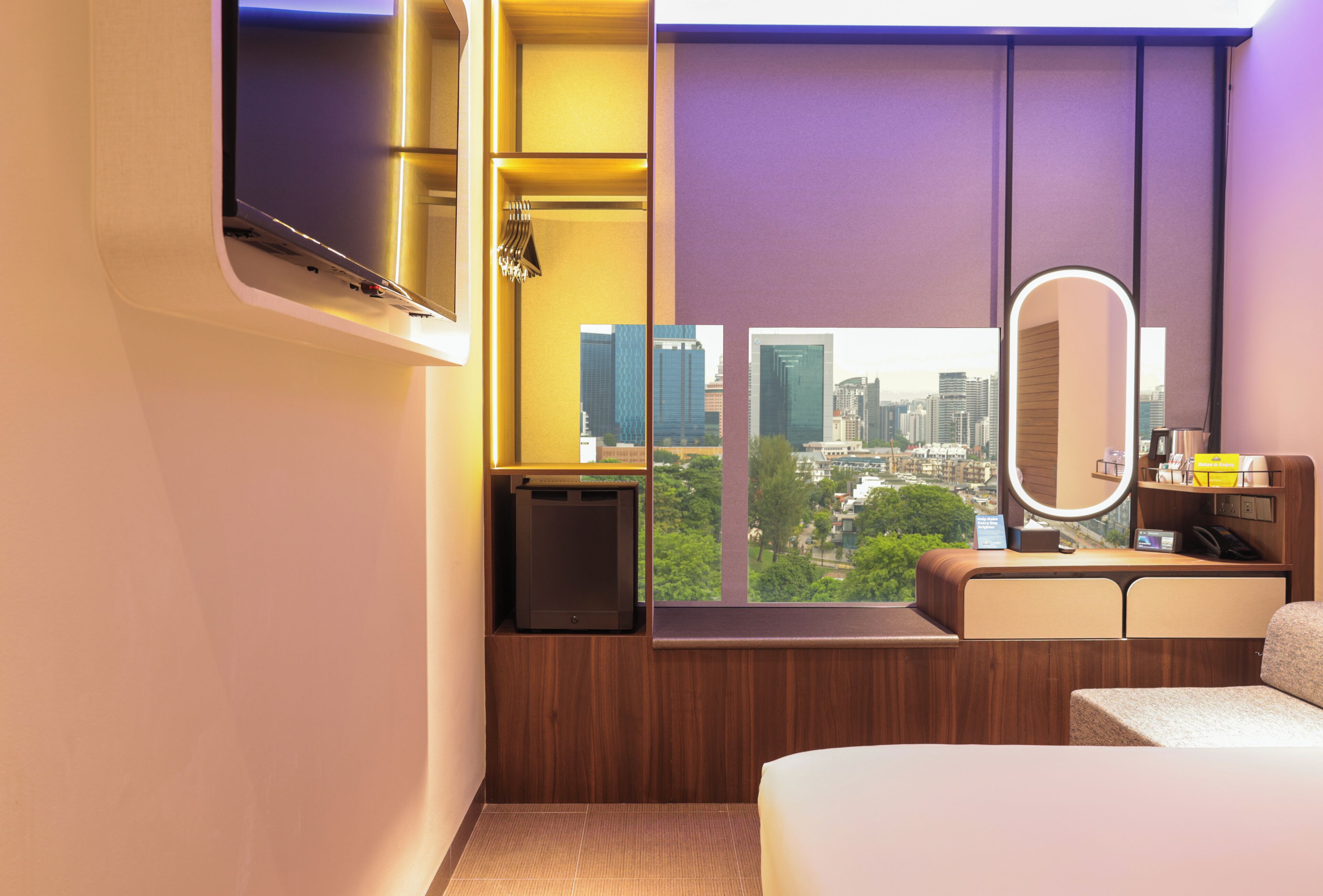 Ein modernes Hotelzimmer mit Blick auf die Stadt, einem integrierten Schminktisch und einem Bett.