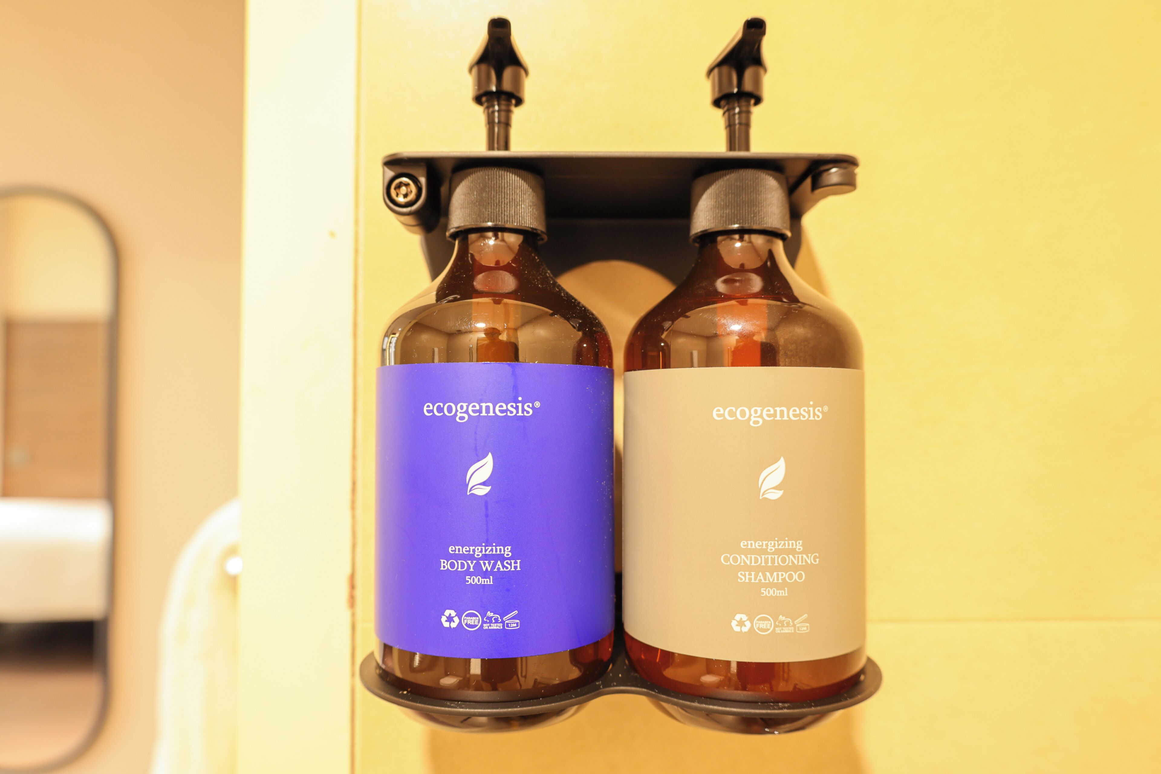 Two bottles of Ecogenesis body wash and shampoo on a shelf.