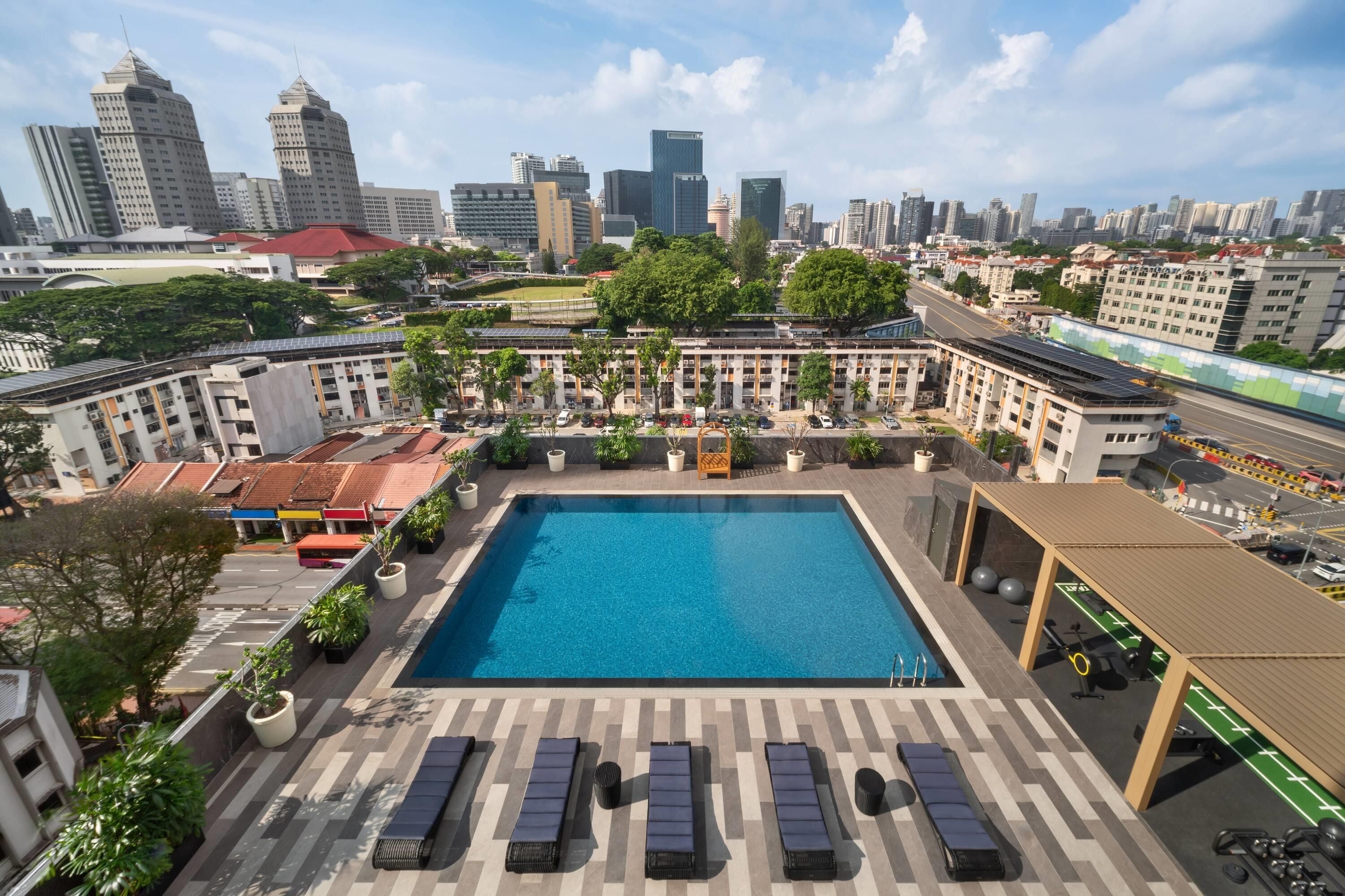 A rooftop pool with lounge chairs and a view of the city skyline.