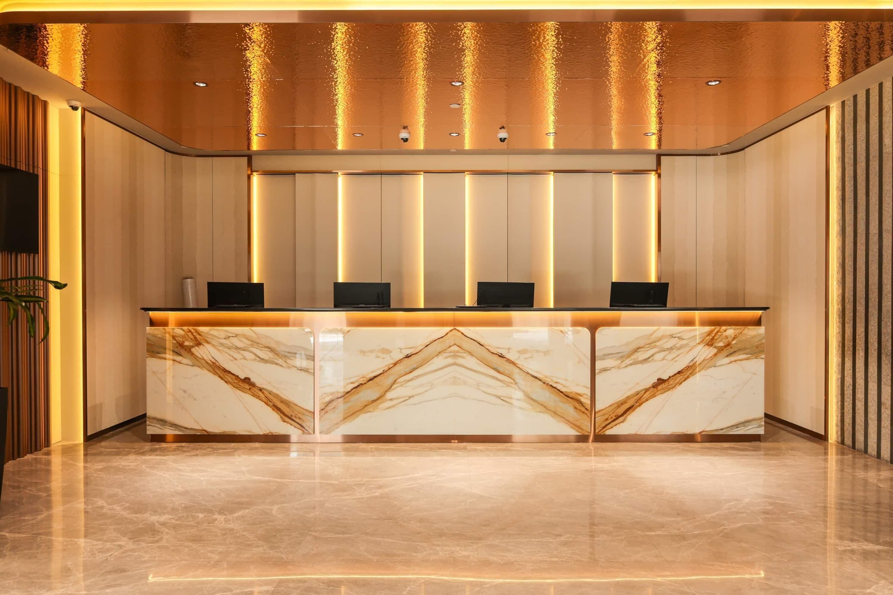 A reception desk with marble top, vertical light panels, and a ceiling with water feature.