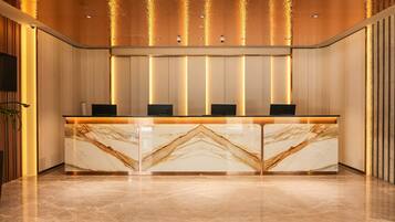 A reception desk with marble top, vertical light panels, and a ceiling with water feature.