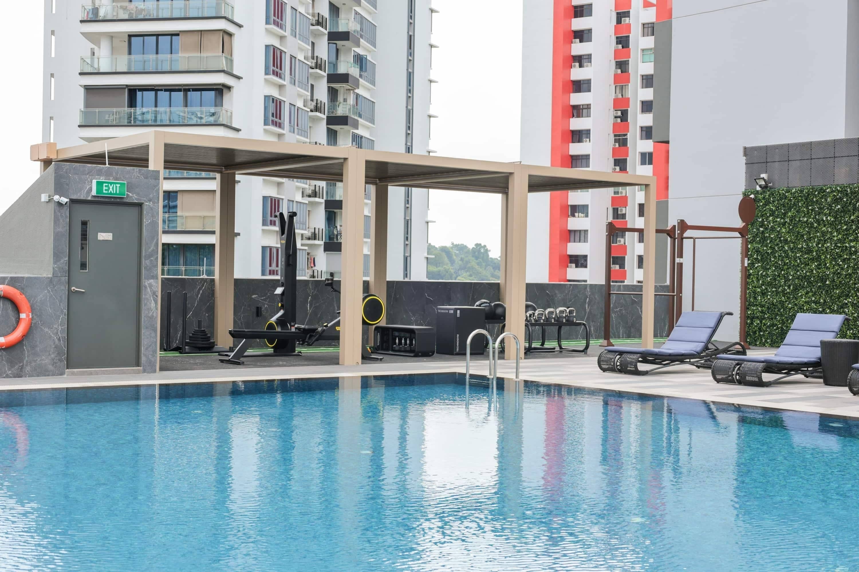 A swimming pool with a covered area, exercise equipment, and lounge chairs.