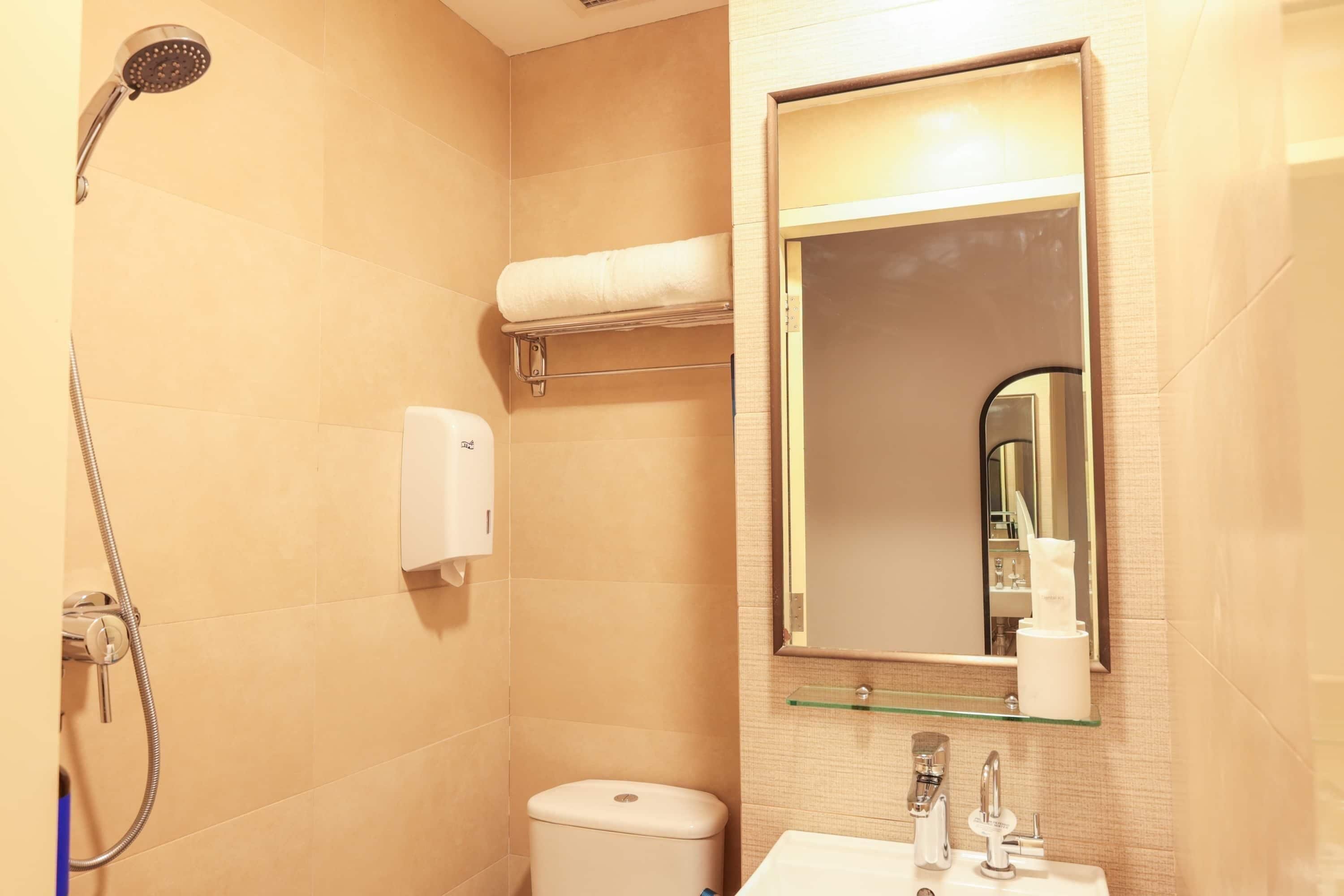 A bathroom with a shower, toilet, sink, and a mirror.