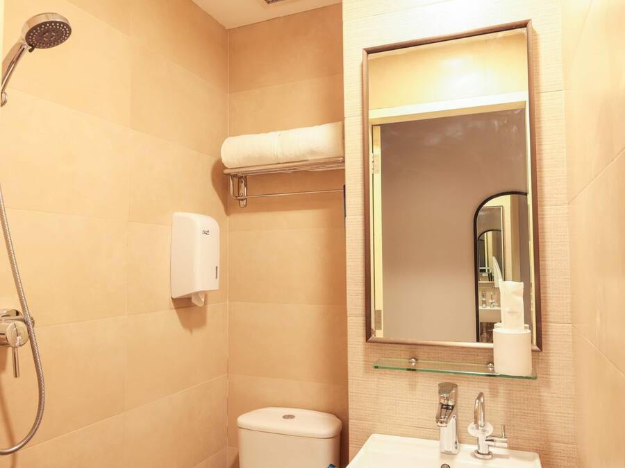A bathroom with a shower, toilet, sink, and a mirror.