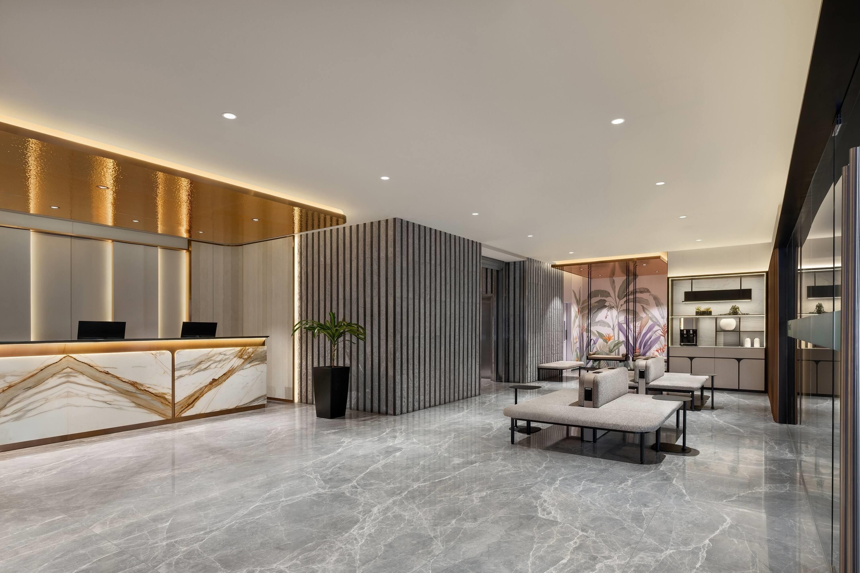 A modern reception area with a marble counter, seating, and a decorative wall.