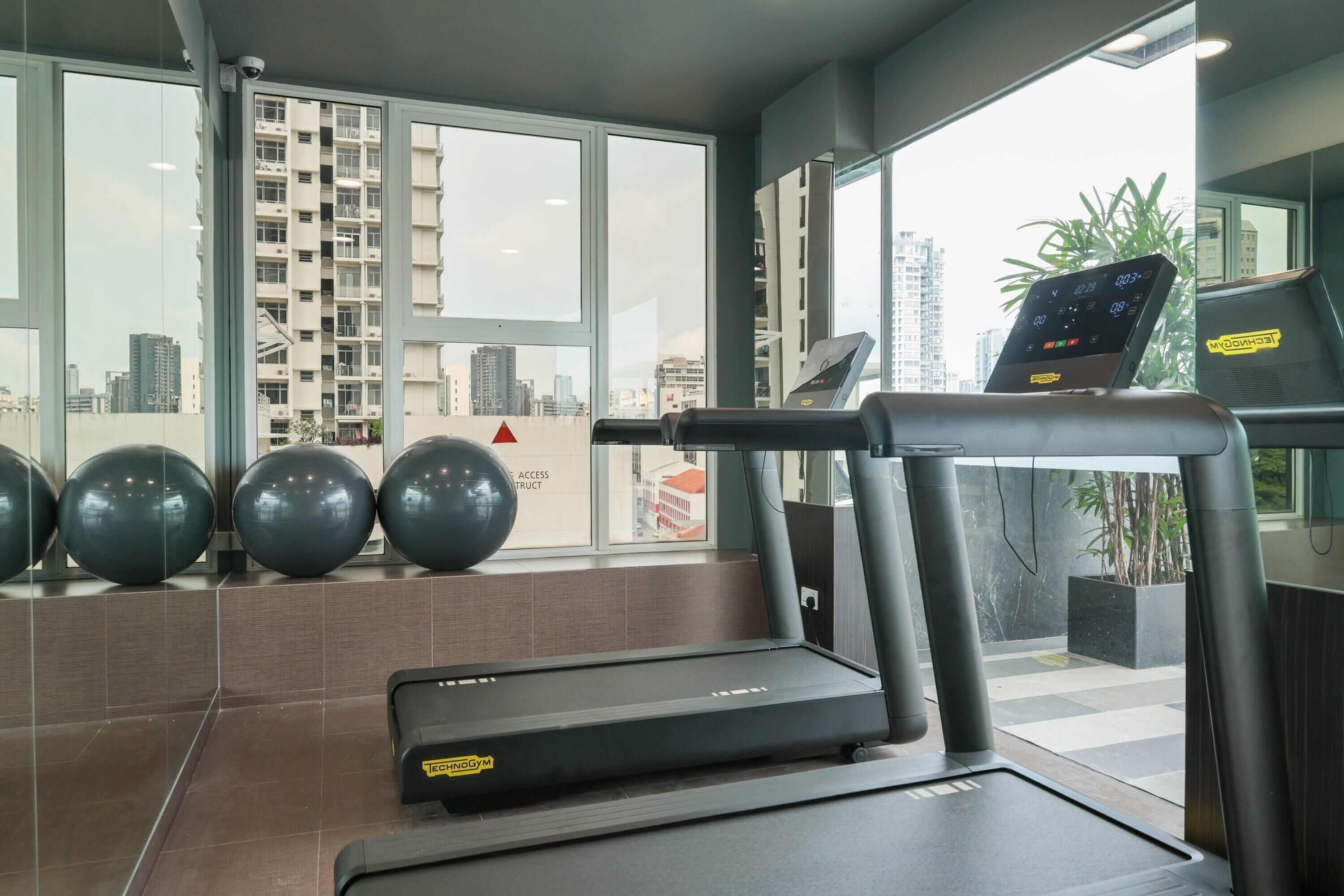 Un gimnasio con cintas de correr, pelotas de ejercicio y una pantalla digital.