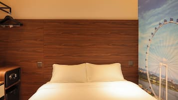 A hotel room with a wooden headboard, a bed with white linens, a wall-mounted safe, and a large window with a view of a Ferris wheel.