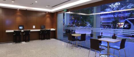A modern indoor area with a reception desk, seating area, and large windows overlooking a street.