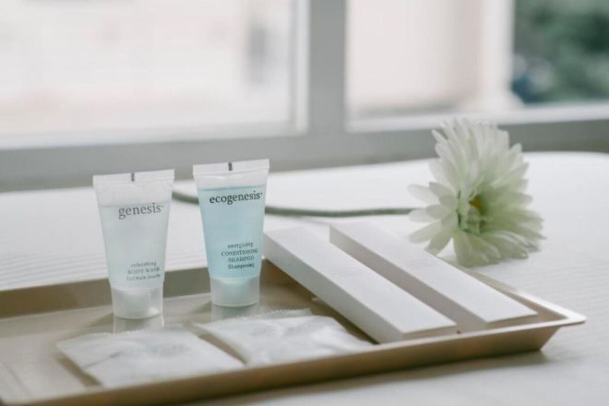 Two skincare product tubes on a tray with a white flower beside them.